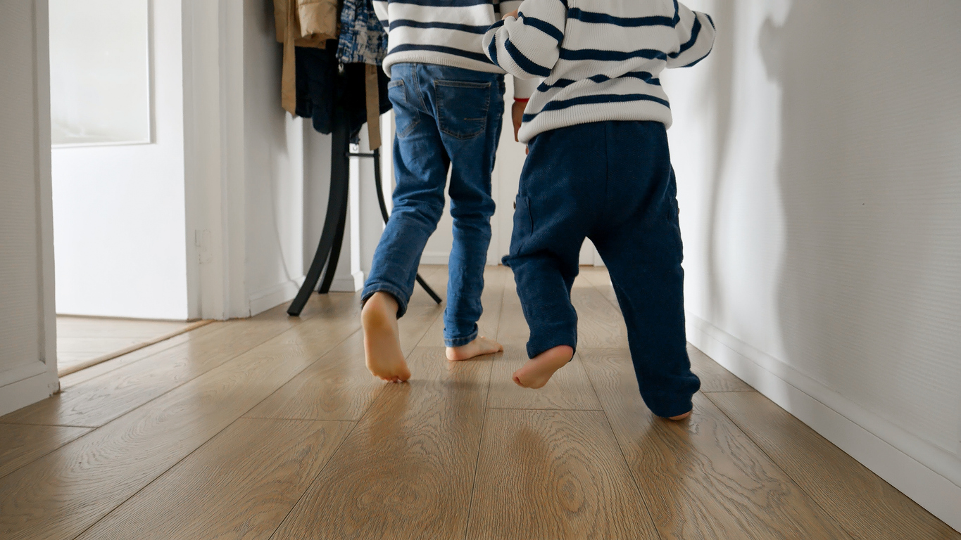 Kids running barefoot on durable luxury vinyl plank flooring in a family home hallway.