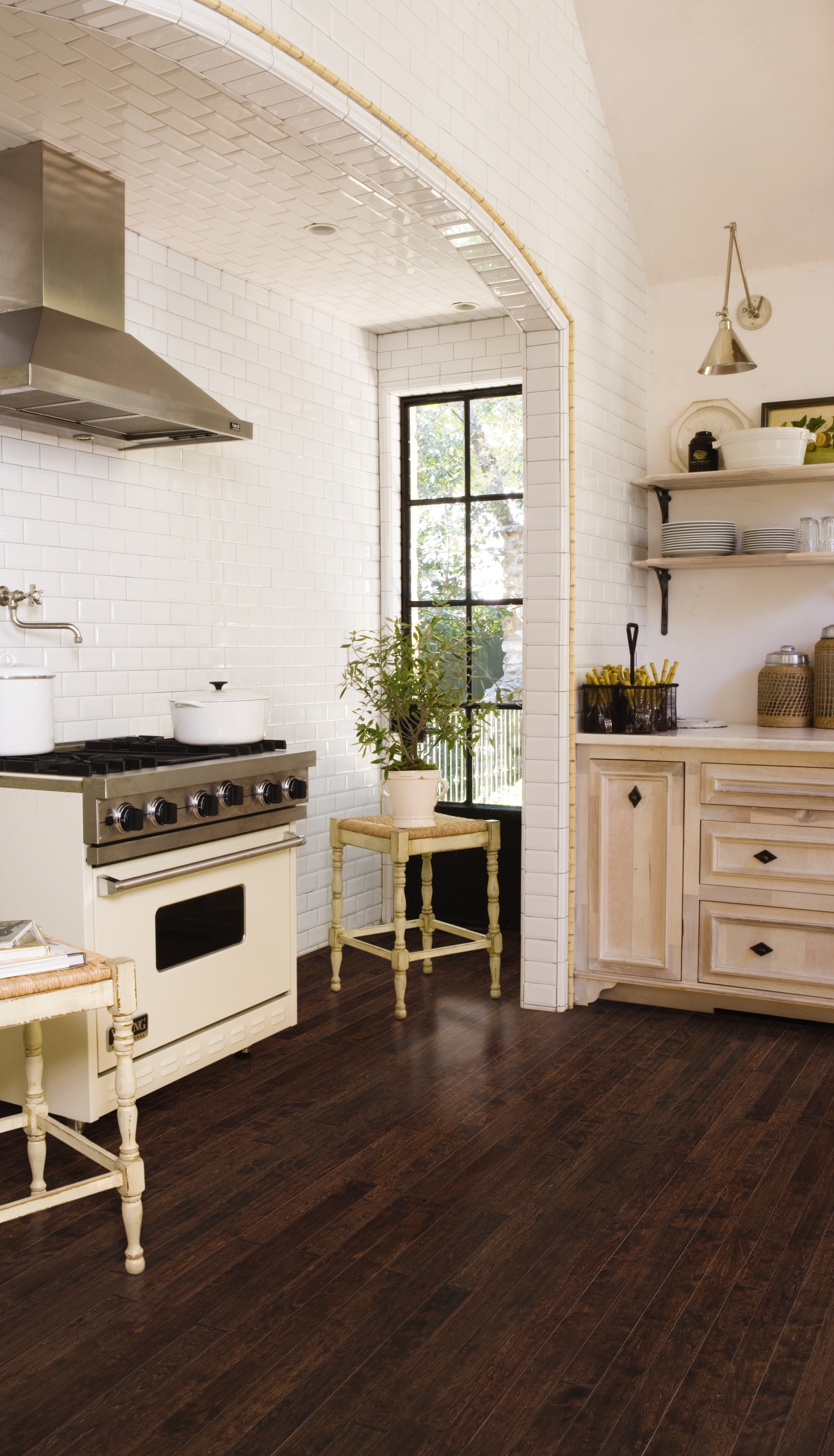 Modern farmhouse kitchen with dark hardwood flooring, white subway tile walls, and natural wood cabinetry.